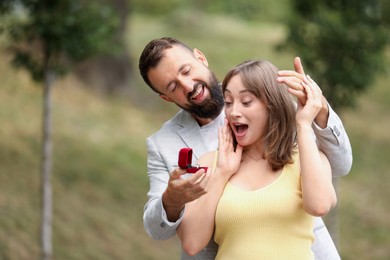 Photo of Man with engagement ring making marriage proposal to his girlfriend outdoors, space for text