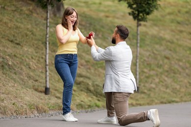 Photo of Man with engagement ring making marriage proposal to his girlfriend outdoors