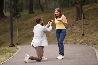 Photo of Man with engagement ring making marriage proposal to his girlfriend outdoors