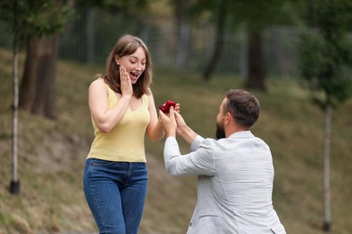 Photo of Man with engagement ring making marriage proposal to his girlfriend outdoors