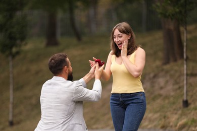 Photo of Man with engagement ring making marriage proposal to his girlfriend outdoors