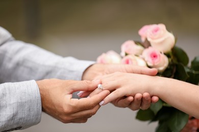 Photo of Making marriage proposal. Man putting engagement ring on his girlfriend's finger outdoors, closeup