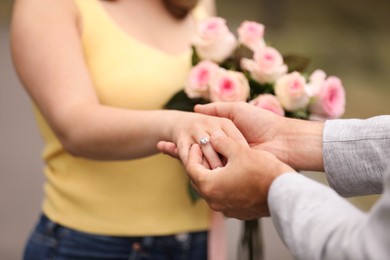 Photo of Making marriage proposal. Man putting engagement ring on his girlfriend's finger outdoors, closeup