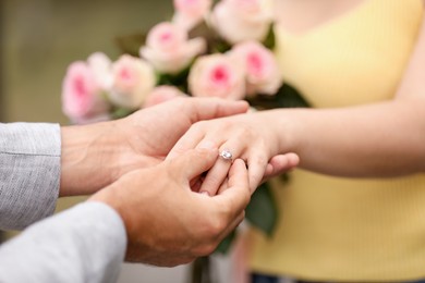 Photo of Making marriage proposal. Man putting engagement ring on his girlfriend's finger outdoors, closeup