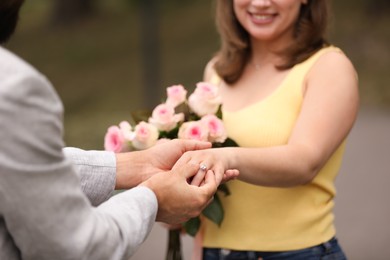 Photo of Making marriage proposal. Man putting engagement ring on his girlfriend's finger outdoors, closeup
