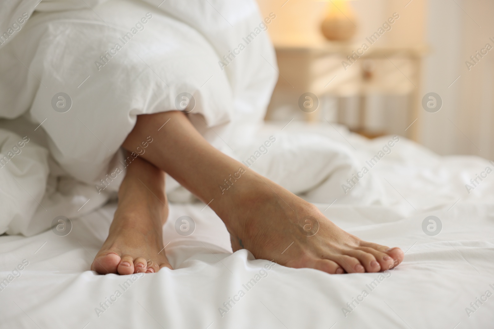 Photo of Woman covering with blanket on bed at home, closeup