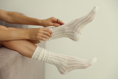 Photo of Woman in socks on sofa near white wall at home, closeup