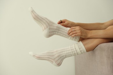 Photo of Woman in socks on sofa near white wall at home, closeup