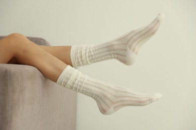 Photo of Woman in socks on sofa near white wall at home, closeup
