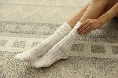 Photo of Woman in socks on carpet with pattern, closeup