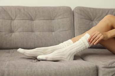 Photo of Woman in socks on grey sofa at home, closeup