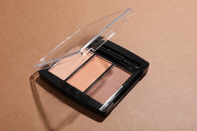Photo of Beautiful eyebrow palette on brown background, closeup