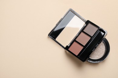 Photo of Eyebrow palette and eyeshadow pan on beige background, top view. Space for text