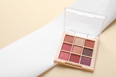 Photo of Beautiful eyeshadow palette on beige background. Space for text