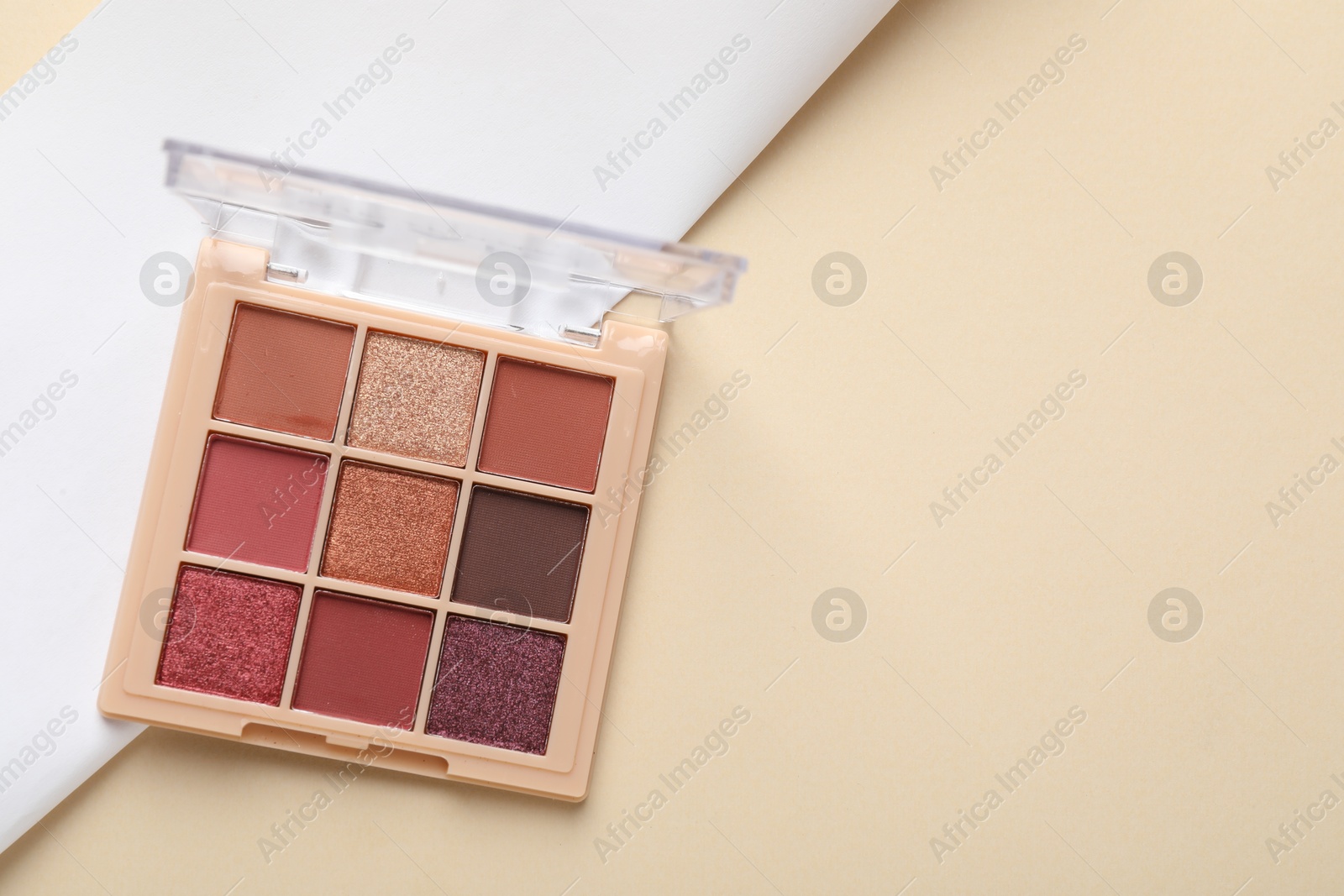 Photo of Beautiful eyeshadow palette on beige background, top view. Space for text