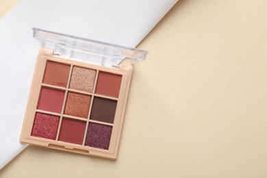 Photo of Beautiful eyeshadow palette on beige background, top view. Space for text