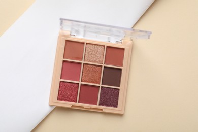 Photo of Beautiful eyeshadow palette on beige background, top view