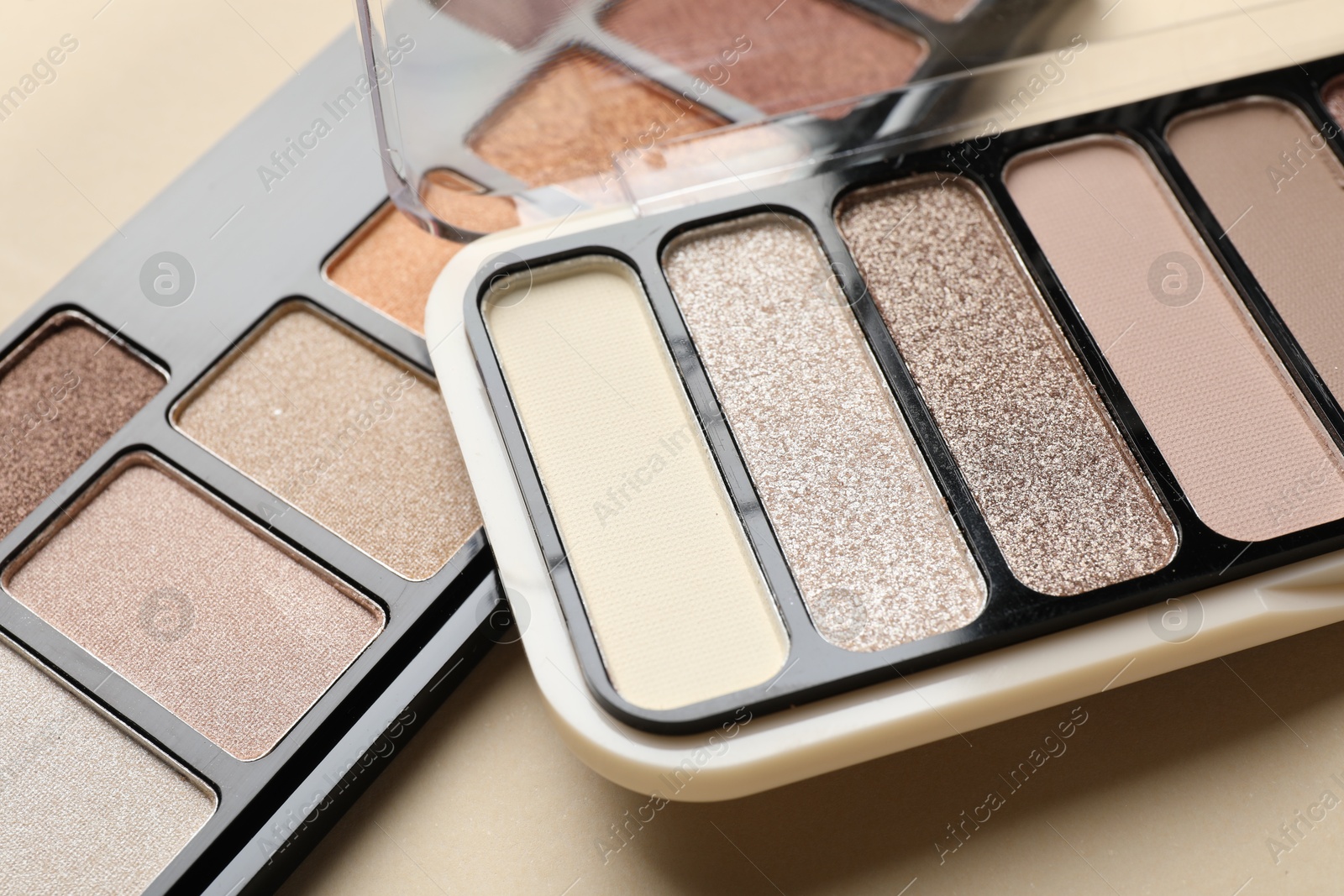 Beautiful eyeshadow palettes on beige background, closeup Photo of Beautiful eyeshadow palettes on beige background, closeup