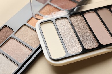 Photo of Beautiful eyeshadow palettes on beige background, closeup
