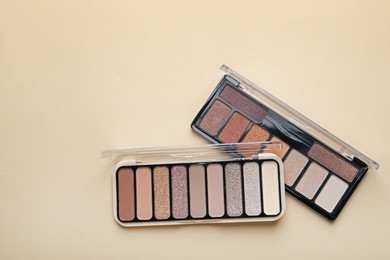 Photo of Beautiful eyeshadow palettes on beige background, top view