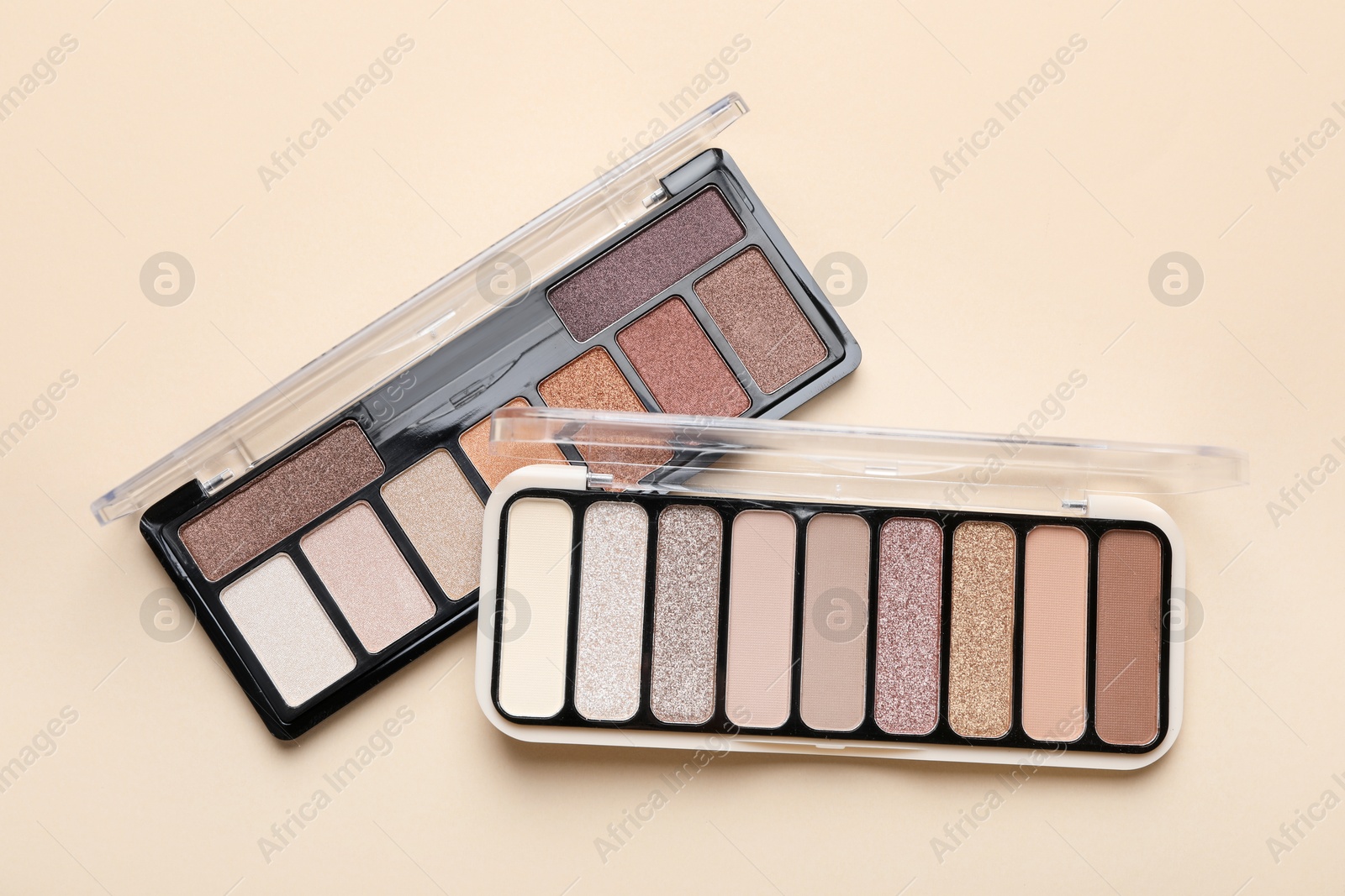 Beautiful eyeshadow palettes on beige background, top view Photo of Beautiful eyeshadow palettes on beige background, top view
