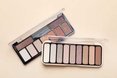 Photo of Beautiful eyeshadow palettes on beige background, top view