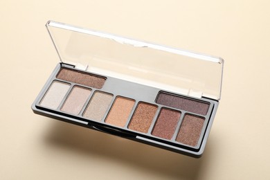Photo of Beautiful eyeshadow palette on beige background, closeup