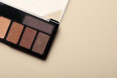 Photo of Beautiful eyeshadow palette on beige background, top view. Space for text