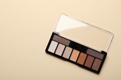 Photo of Beautiful eyeshadow palette on beige background, top view. Space for text