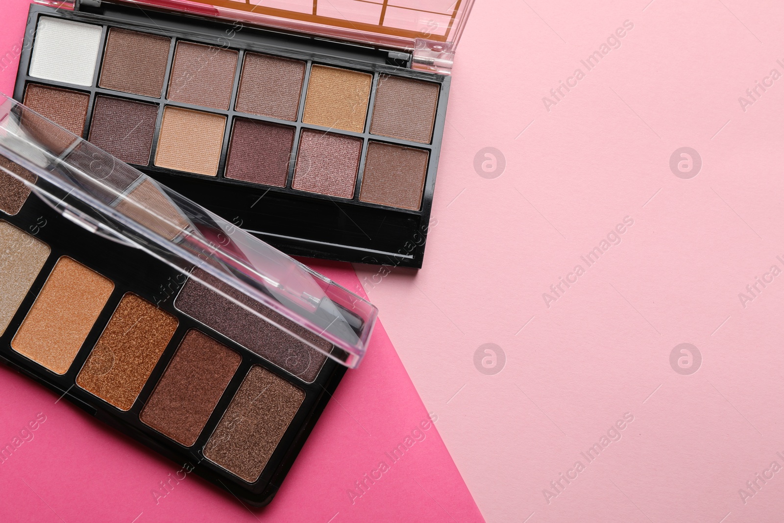 Photo of Beautiful eyeshadow palettes on pink background, top view. Space for text