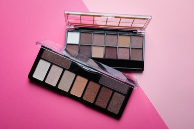 Photo of Beautiful eyeshadow palettes on pink background, top view