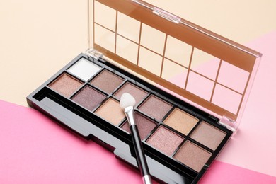 Photo of Beautiful eyeshadow palette with applicator on color background, closeup