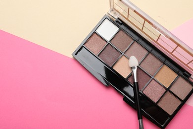 Photo of Beautiful eyeshadow palette with applicator on color background, top view. Space for text