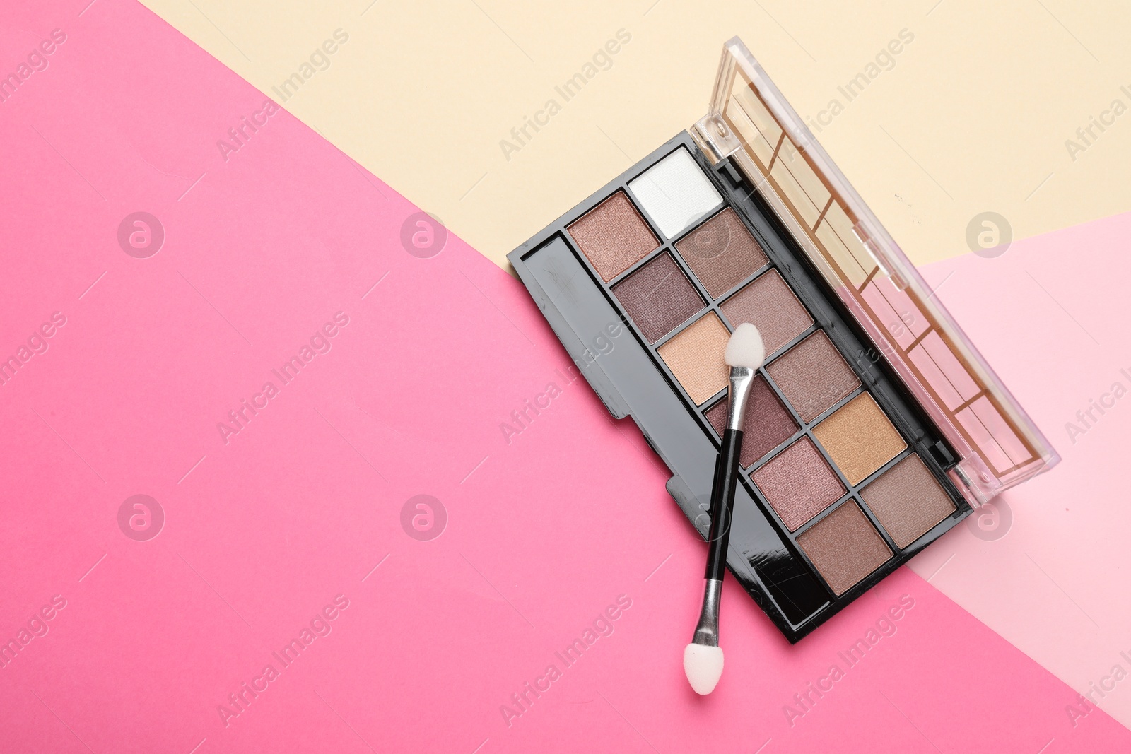 Photo of Beautiful eyeshadow palette with applicator on color background, top view. Space for text