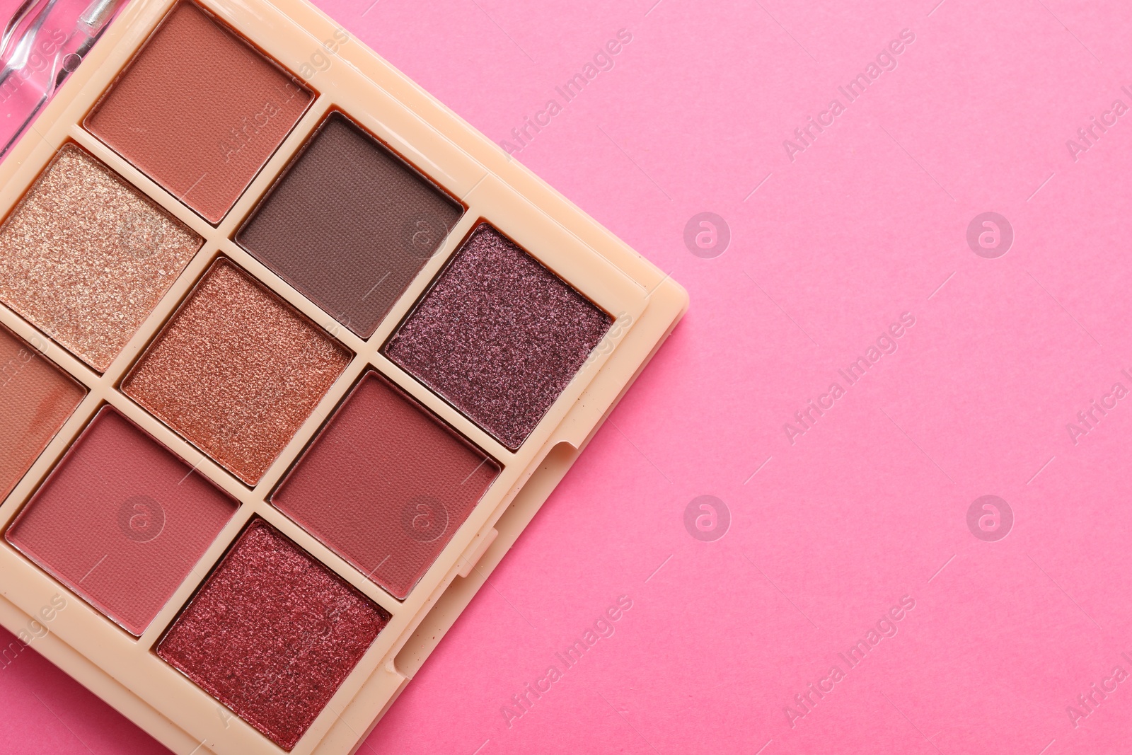 Photo of Beautiful eyeshadow palette on pink background, top view. Space for text