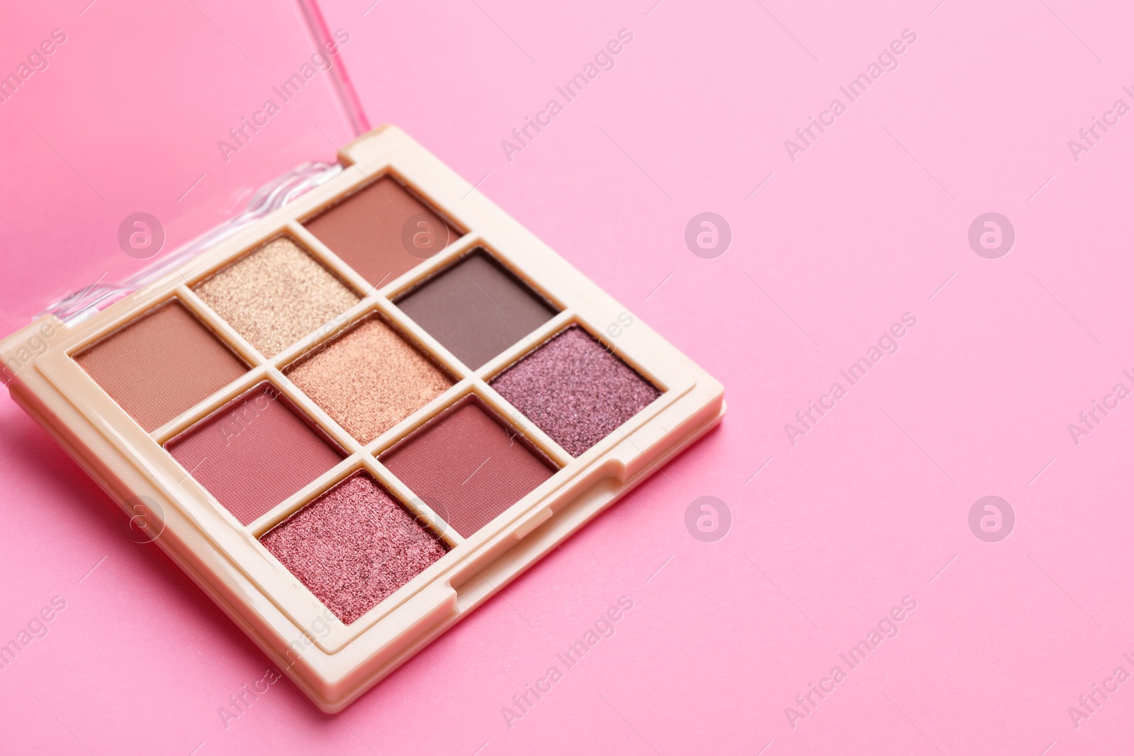 Photo of Beautiful eyeshadow palette on pink background, closeup. Space for text