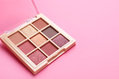 Photo of Beautiful eyeshadow palette on pink background, closeup. Space for text