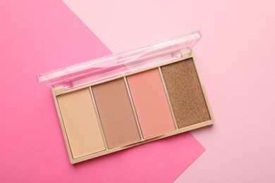 Photo of Beautiful contouring palette on pink background, top view