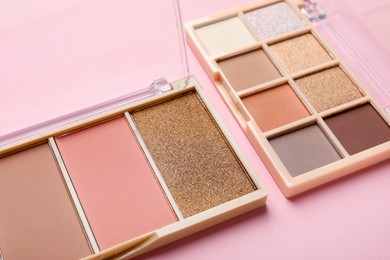 Photo of Beautiful eyeshadow palettes on light pink background, closeup