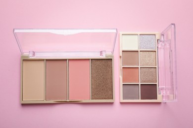 Photo of Beautiful eyeshadow palettes on light pink background, top view