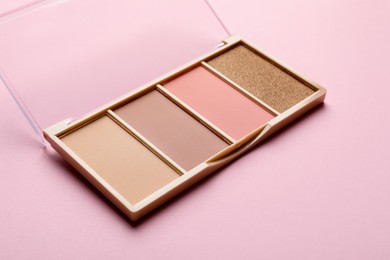Photo of Beautiful contouring palette on light pink background, closeup