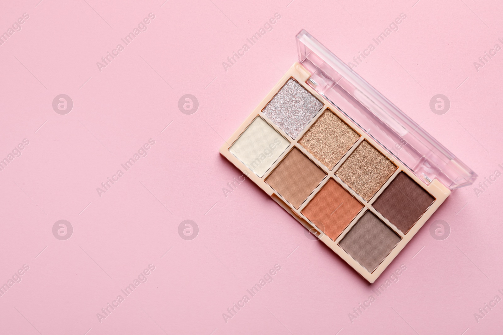 Photo of Beautiful eyeshadow palette on light pink background, top view. Space for text