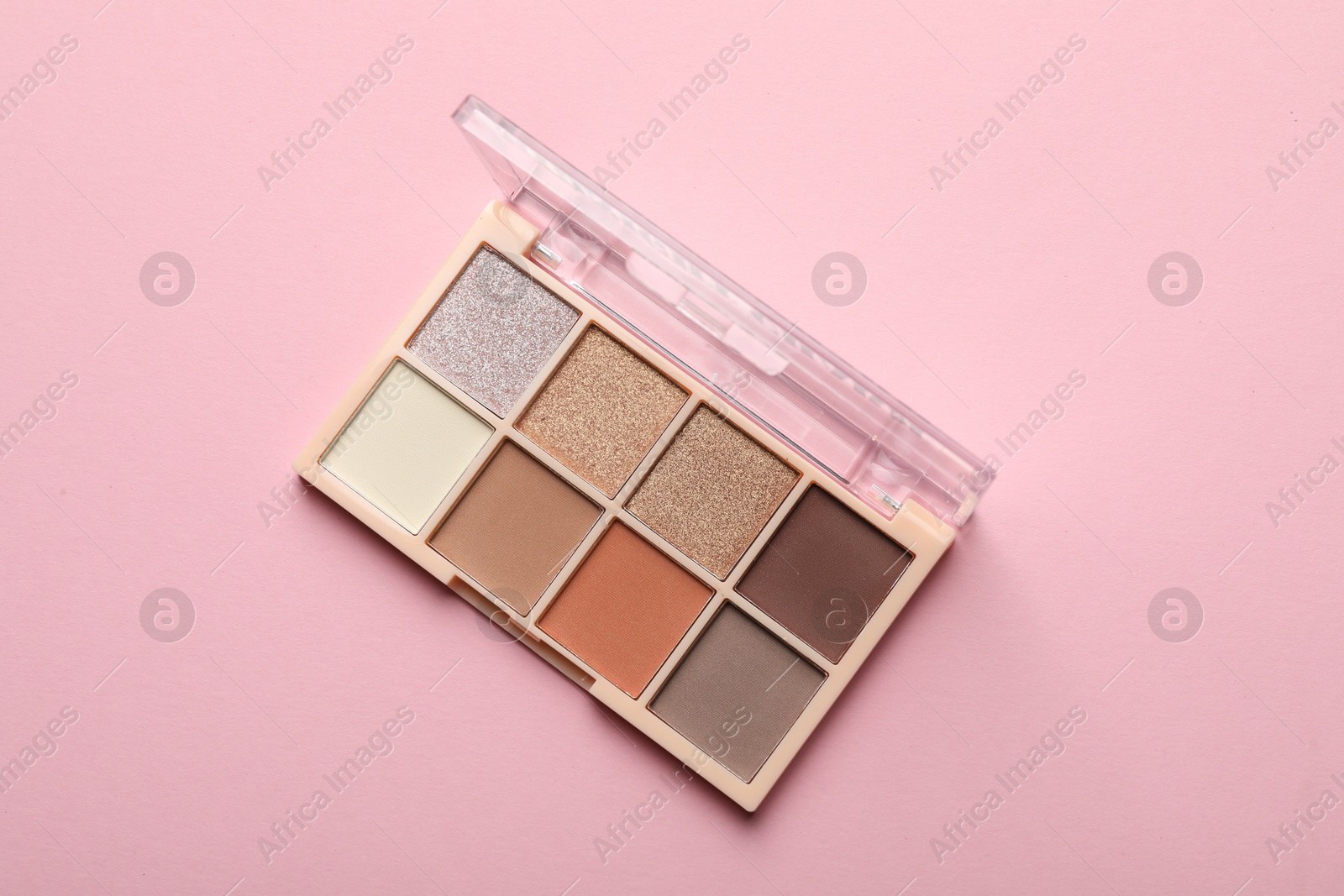 Photo of Beautiful eyeshadow palette on light pink background, top view