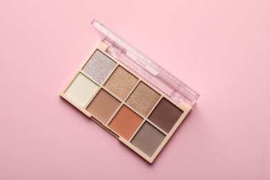 Photo of Beautiful eyeshadow palette on light pink background, top view
