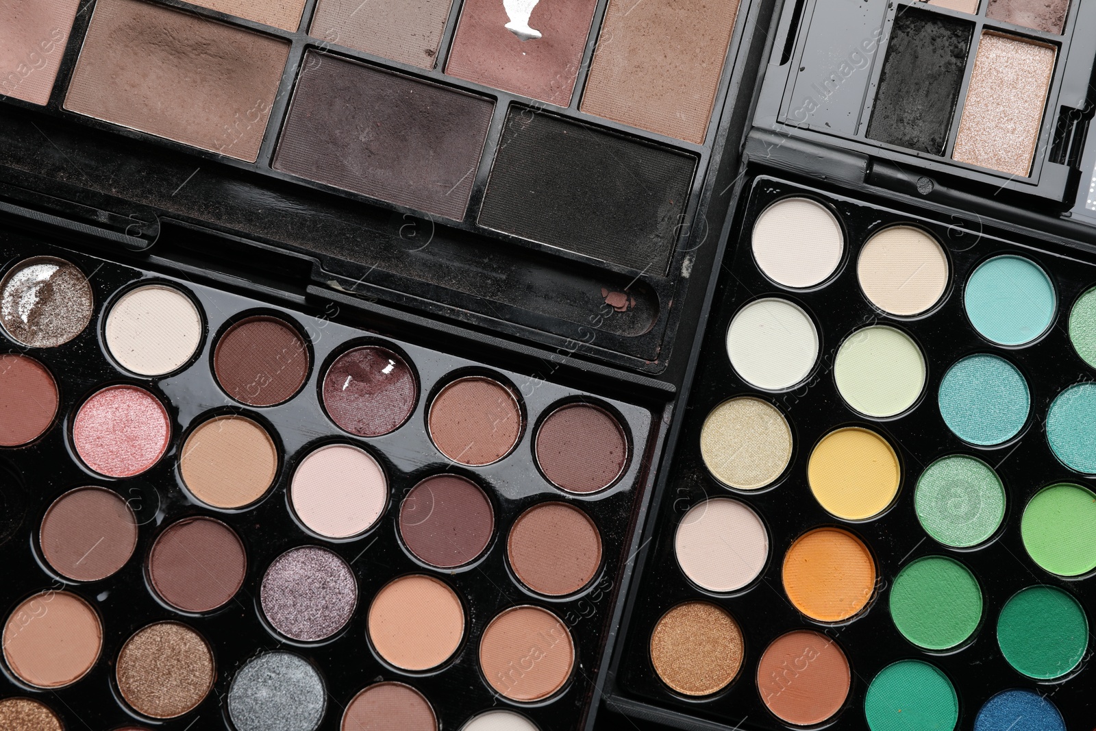 Photo of Different used eyeshadow palettes as background, closeup