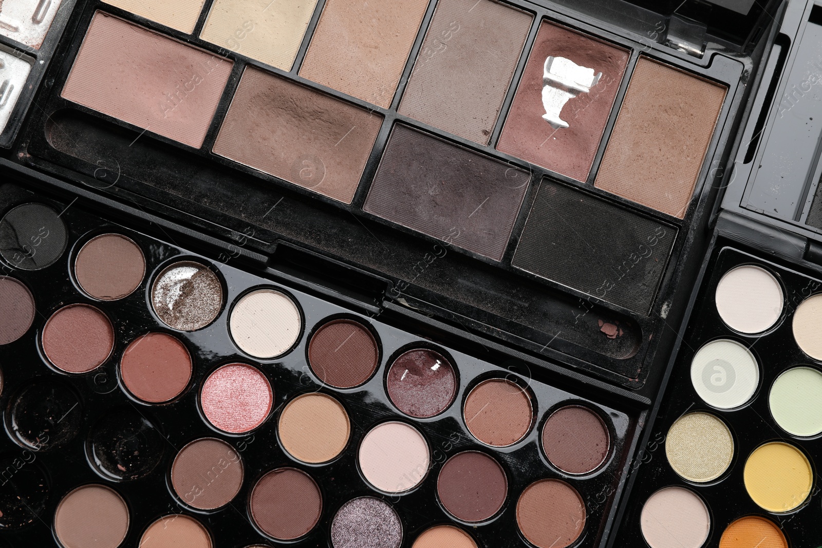 Photo of Different used eyeshadow palettes as background, closeup