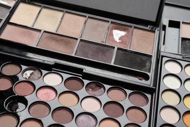 Photo of Different used eyeshadow palettes as background, closeup