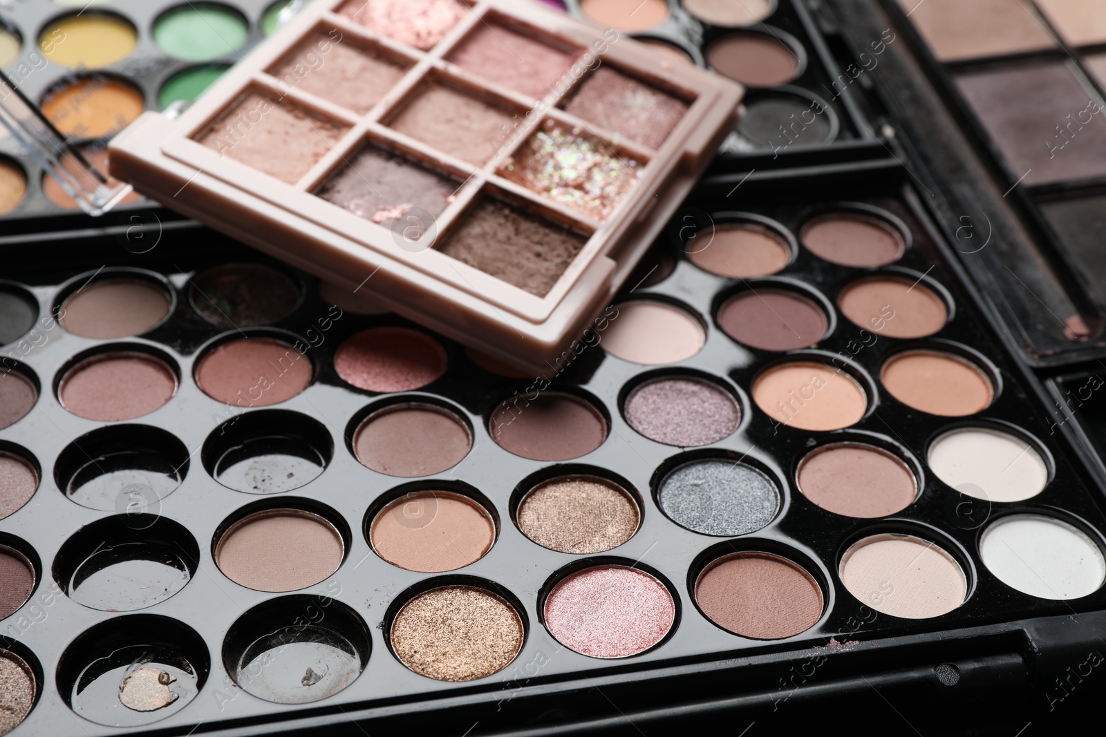 Photo of Different used eyeshadow palettes as background, closeup