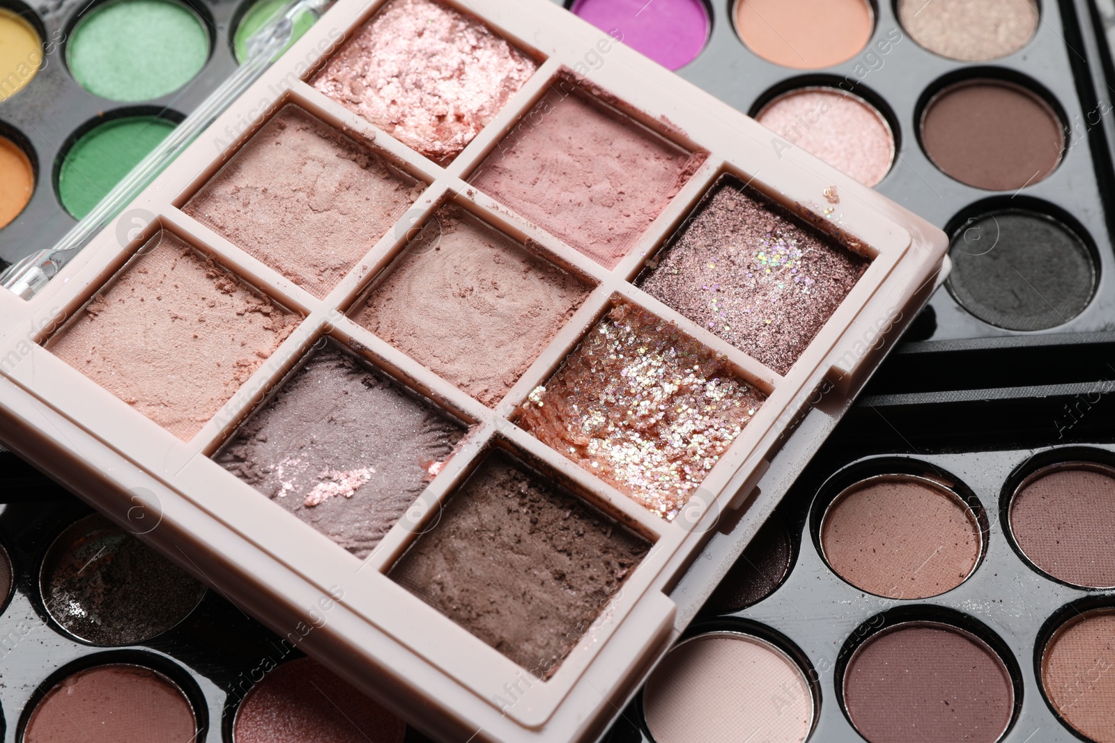Photo of Different used eyeshadow palettes as background, closeup