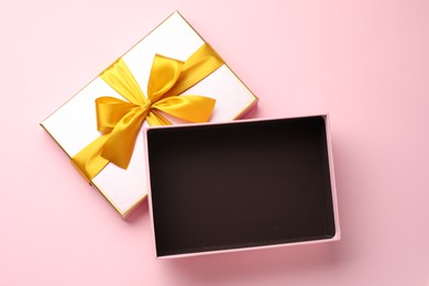 Photo of Open gift box with beautiful lid on pink background, top view